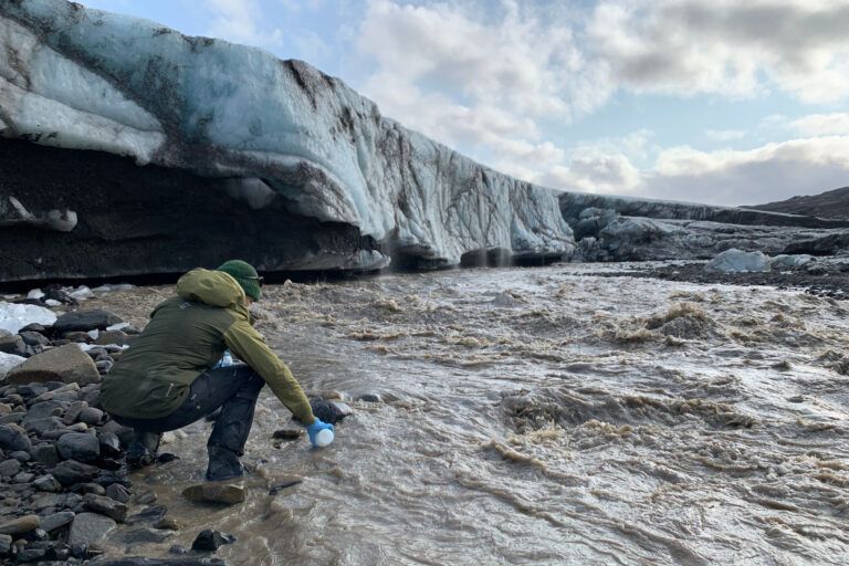 Eine Wissenschaftlerin nimmt am Gletscherende eine Wasserprobe aus dem Gletscherfluss Svalbreen. © Gabrielle Kleber (UiT, iC3)