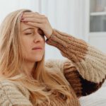Frau hält sich den Kopf