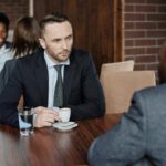 Zwei Männer sitzen sich in einem Café an einem Tisch gegenüber.