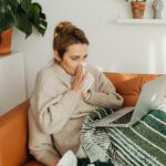 Kranke Frau mit Laptop auf der Couch