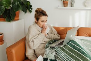 Kranke Frau mit Laptop auf der Couch