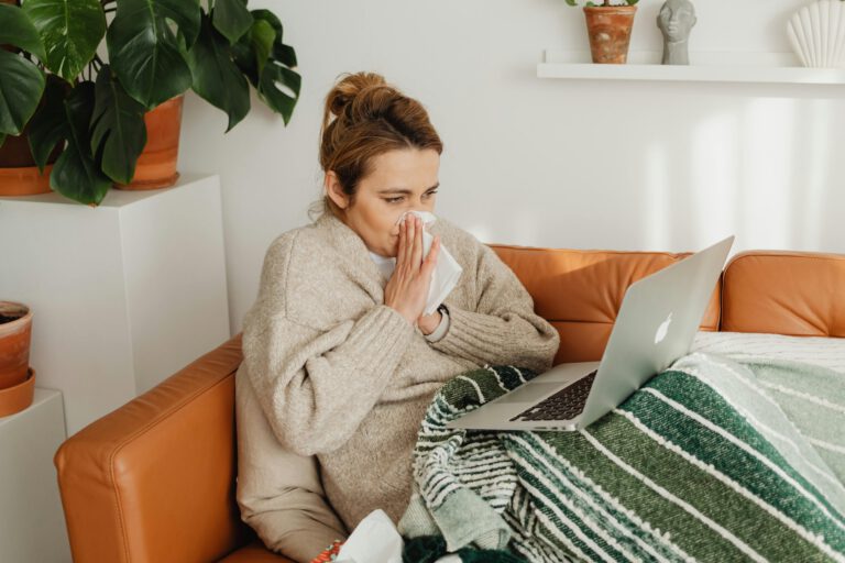 Kranke Frau mit Laptop auf der Couch