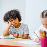 Kind sitzt abwesend in der Schule am Tisch