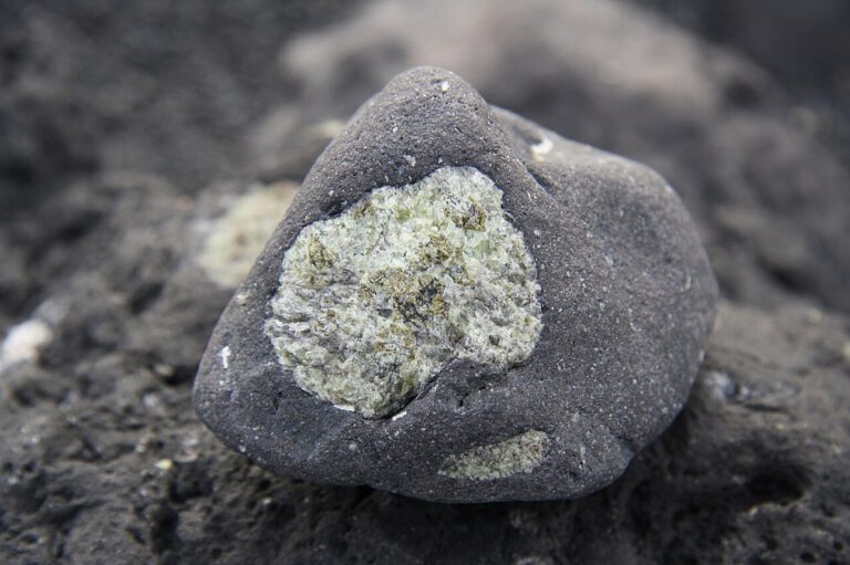 Ein Olivineinschluss steckt in erstarrter Lava – das magnesiumreiche Mineral aus dem Erdmantel reagiert an der Erdoberfläche vergleichsweise leicht mit Säuren und kann dabei Metalle freisetzen.